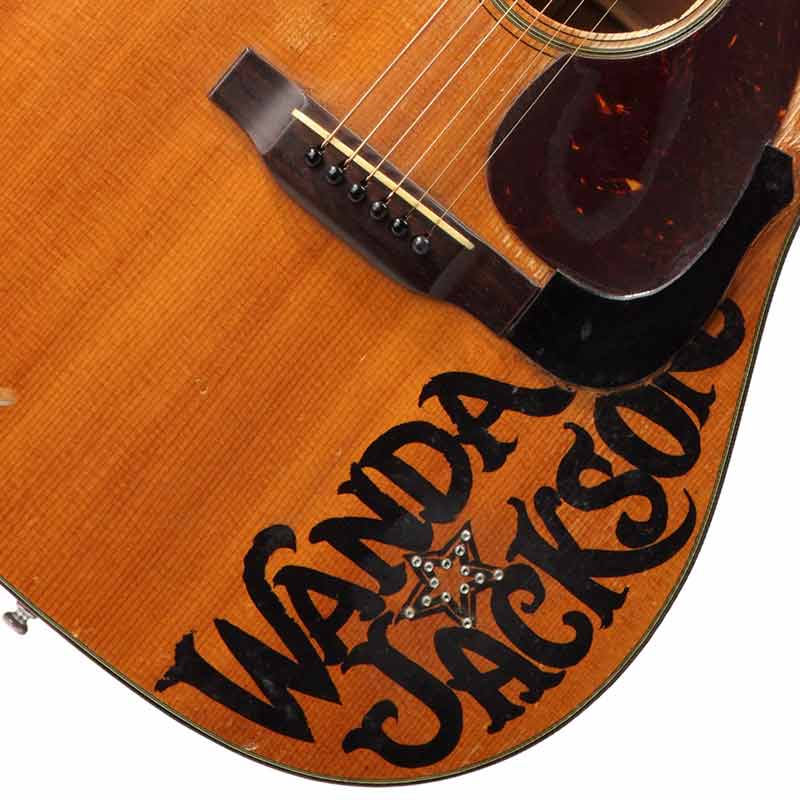 Zoom of Wanda Jackson's name painted boldly in black on her guitar.